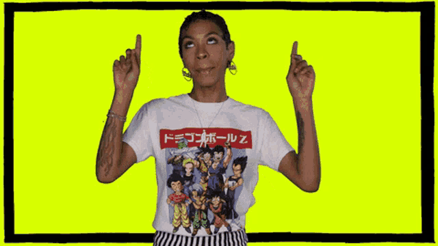 a woman wearing a dragon ball z shirt points up