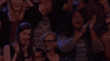 a group of people are sitting in a dark room clapping .