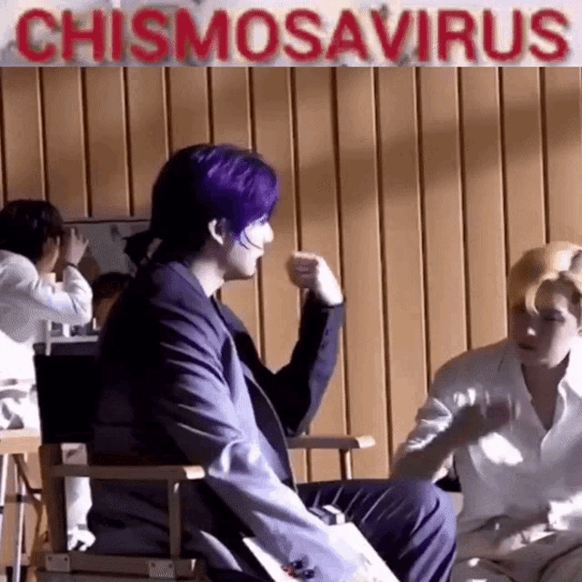 a man with purple hair is sitting in a director 's chair