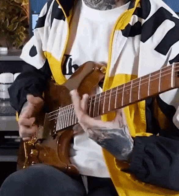 a man with a tattoo on his arm is playing a guitar .