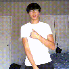 a young man wearing glasses and a white shirt is giving a thumbs up sign