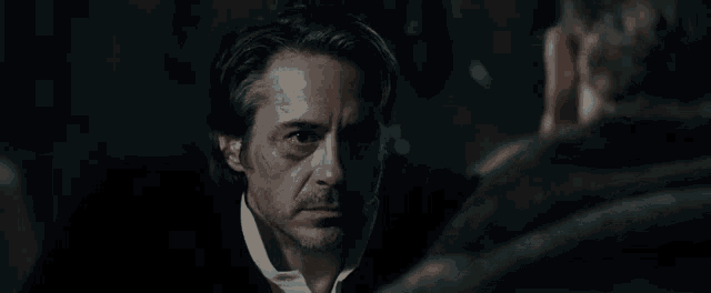 a man with a black eye is looking at another man in the mirror .