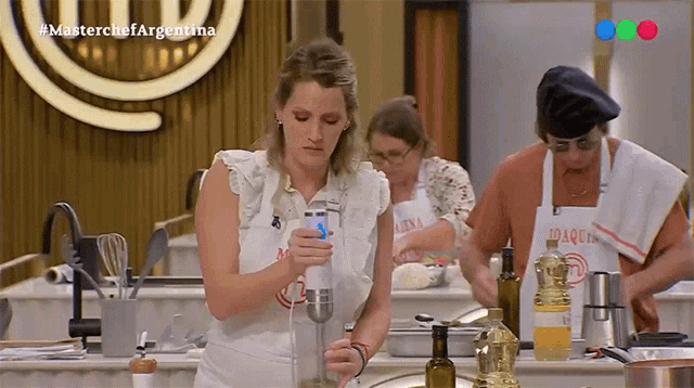 a woman using a blender in front of a sign that says #masterchefargentina