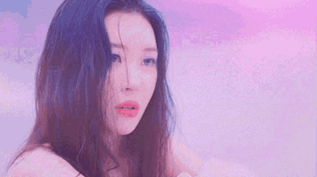 a close up of a woman 's face with long hair against a purple sky .