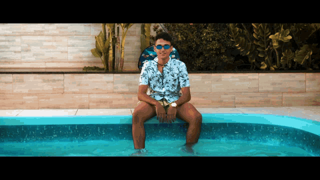 a man is sitting in a pool wearing sunglasses
