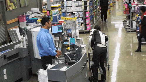 a man in a blue shirt stands behind a counter in a store