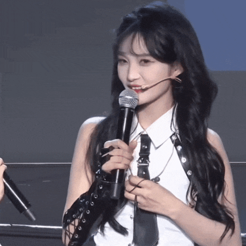 a woman with long hair is holding a microphone in her hand