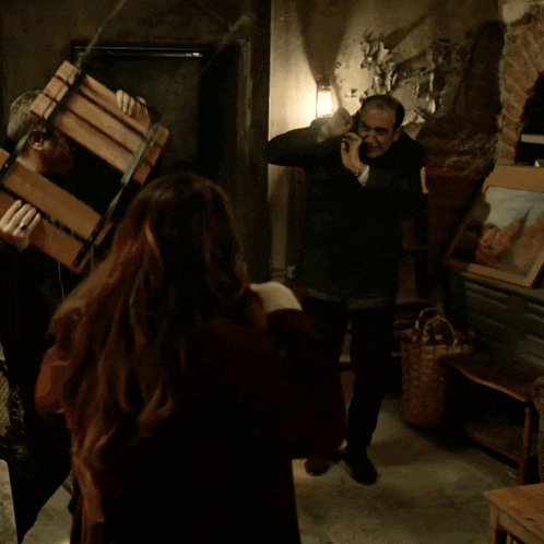 a group of people are standing in a dark room with a painting on the wall