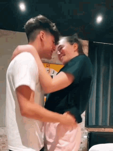 a man and a woman are kissing in a room .