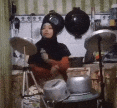 a woman wearing a hijab is playing drums in a kitchen