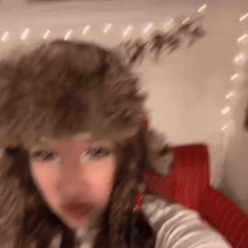 a woman wearing a furry hat is taking a selfie .