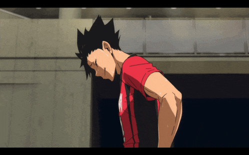 a man with black hair and a red shirt is standing with his hands on his hips