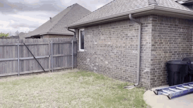 a blue ladder sits on the side of a brick house