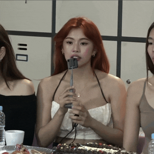 a girl with red hair is holding a microphone in her hand