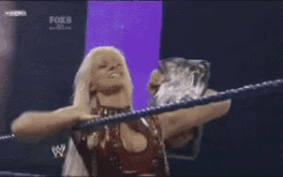 a female wrestler is holding a trophy in a ring