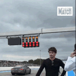 a man stands in front of a car and a sign that says paris match on it