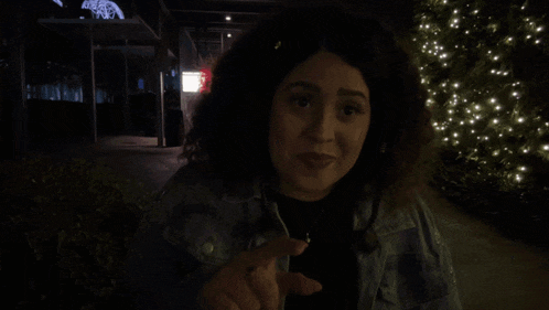 a woman in a denim jacket is smiling and giving a thumbs up in front of a sign that says " shagarita "