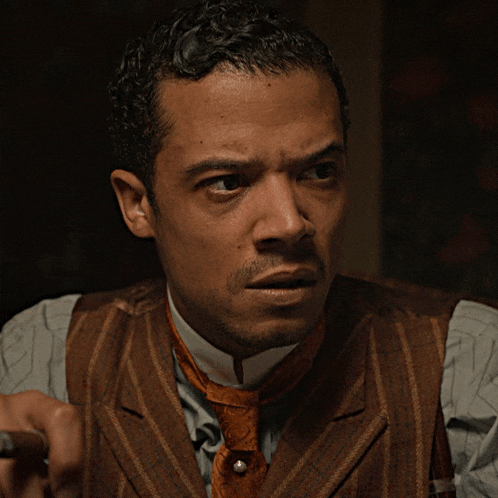 a man in a suit and tie holds a cigar