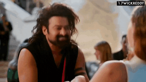a man with a beard is talking to a woman in a crowded room .