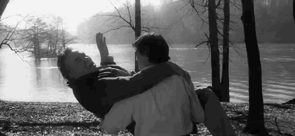 a black and white photo of a man carrying another man in his arms .