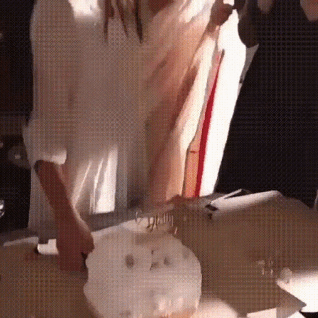 a woman in a white shirt is cutting a cake with the word glam on it .