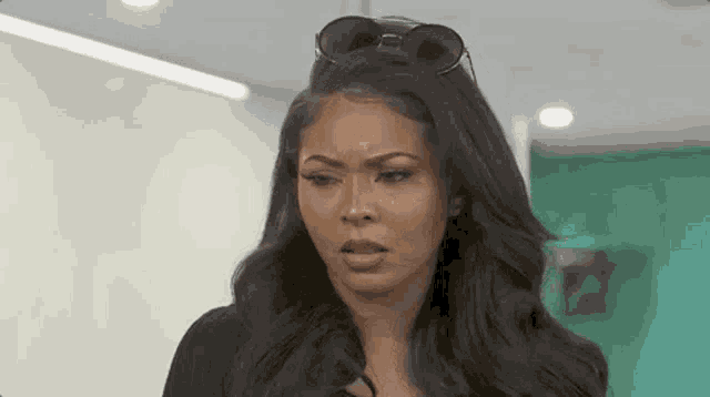 a woman wearing sunglasses and a black shirt is making a surprised face .