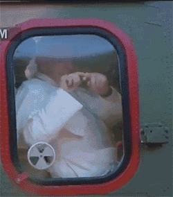 a man is looking out of a window with the letter m on the bottom