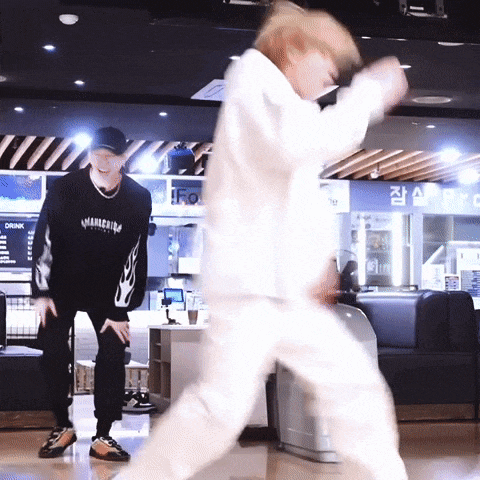 two men are dancing in a room with a drink menu on the wall behind them