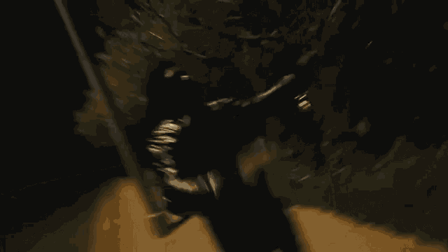 a man in a black suit is standing in the dark .