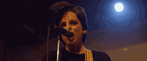 a man is singing into a microphone while playing a guitar