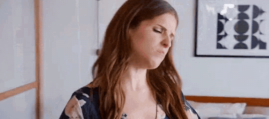 a woman is making a funny face in front of a bed .
