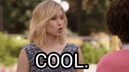 a woman is talking to another woman while holding a sign that says cool .