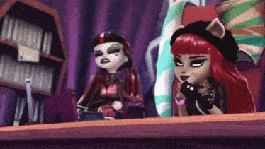 two monster high dolls are sitting at a table and talking on a phone .