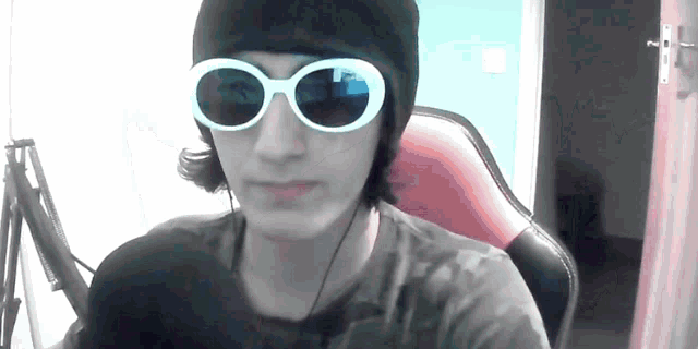 a young man wearing sunglasses and a black hat