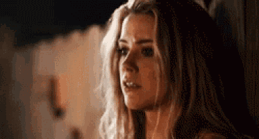 a woman with long blonde hair is standing in front of a wall and looking at the camera .