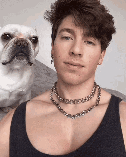 a man wearing a chain around his neck is standing next to a dog