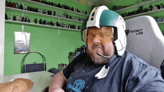 a man wearing a helmet and goggles is sitting in a chair that says secret lab