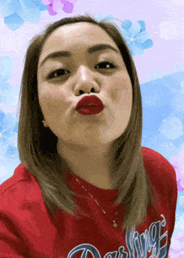 a woman wearing a red darling shirt is making a funny face