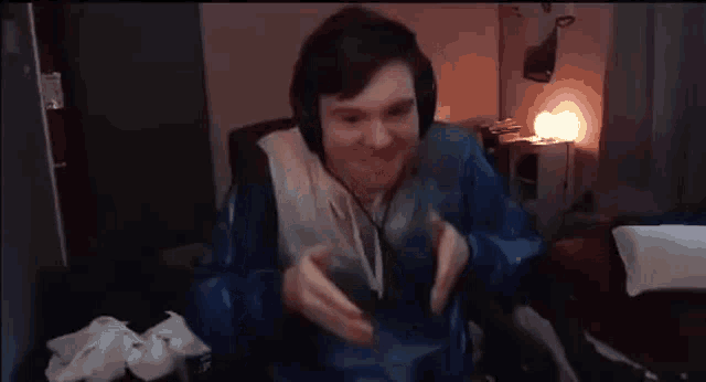 a man wearing headphones and a blue jacket is sitting in a room .