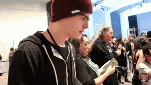 a man wearing a beanie that says ' abercrombie & fitch ' on it stands in a crowd of people