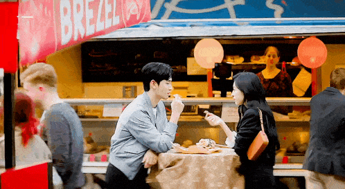 a man and woman are sitting at a table in front of a food truck .