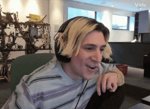 a man wearing headphones is smiling in front of a sign that says ' victu ' on it