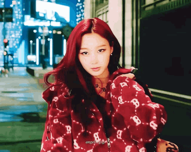 a woman with red hair is wearing a red jacket with letters b and a on it