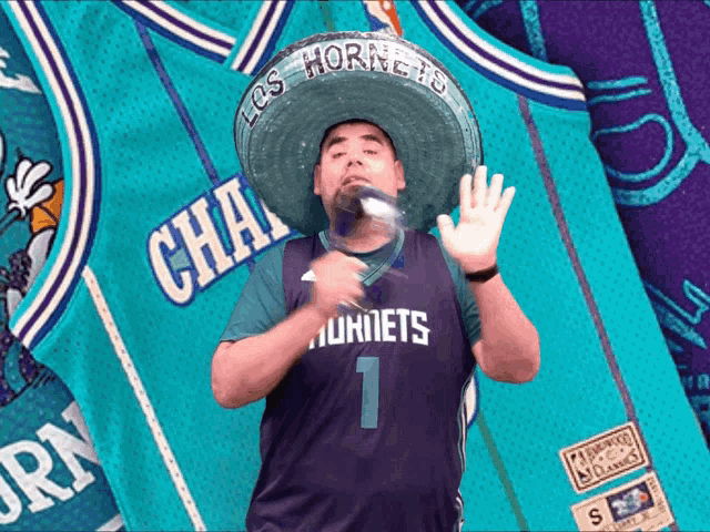 a man wearing a hornets jersey and sombrero