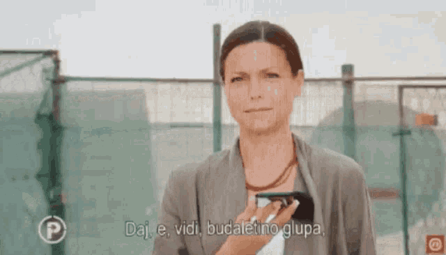 a woman is holding a cell phone and says daj e vidi budaletino glupa in a foreign language