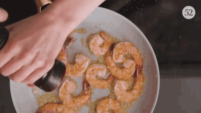 a plate of shrimp is being sprinkled with salt and pepper