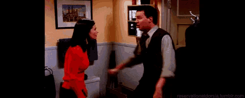 a man and a woman are standing in a bathroom talking to each other .