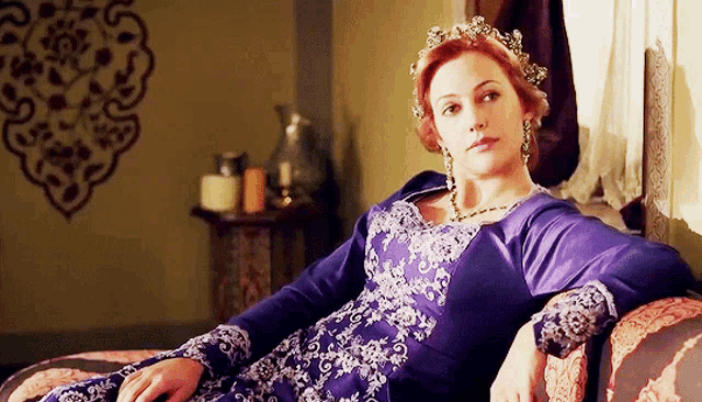a woman in a purple dress is sitting on a chair