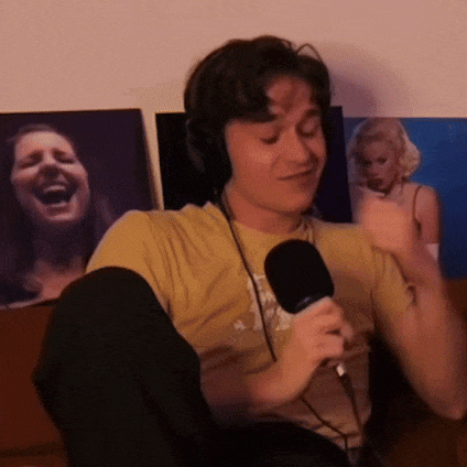 a man wearing headphones is holding a microphone in front of a laughing woman