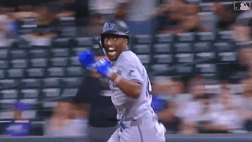 a baseball player wearing a helmet and gloves is running on a baseball field .